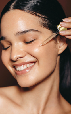 a woman applying oil and smiling with her eyes closed