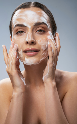 a woman applying foaming face wash